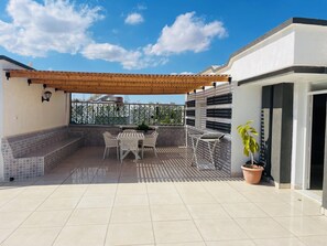 A covered patio with tiled flooring, a wooden pergola, a seating area with a table and chairs, and a potted plant. - Enjoy an unforgettable stay in this bright apartment with terrace (Mahdia)