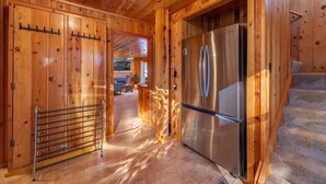 A wooden interior with a stainless steel refrigerator, a metal rack, and a fireplace. - Tahoe Golf Cabin | Walk to Beach, Hot Tub, EV & AC (Tahoe Vista)