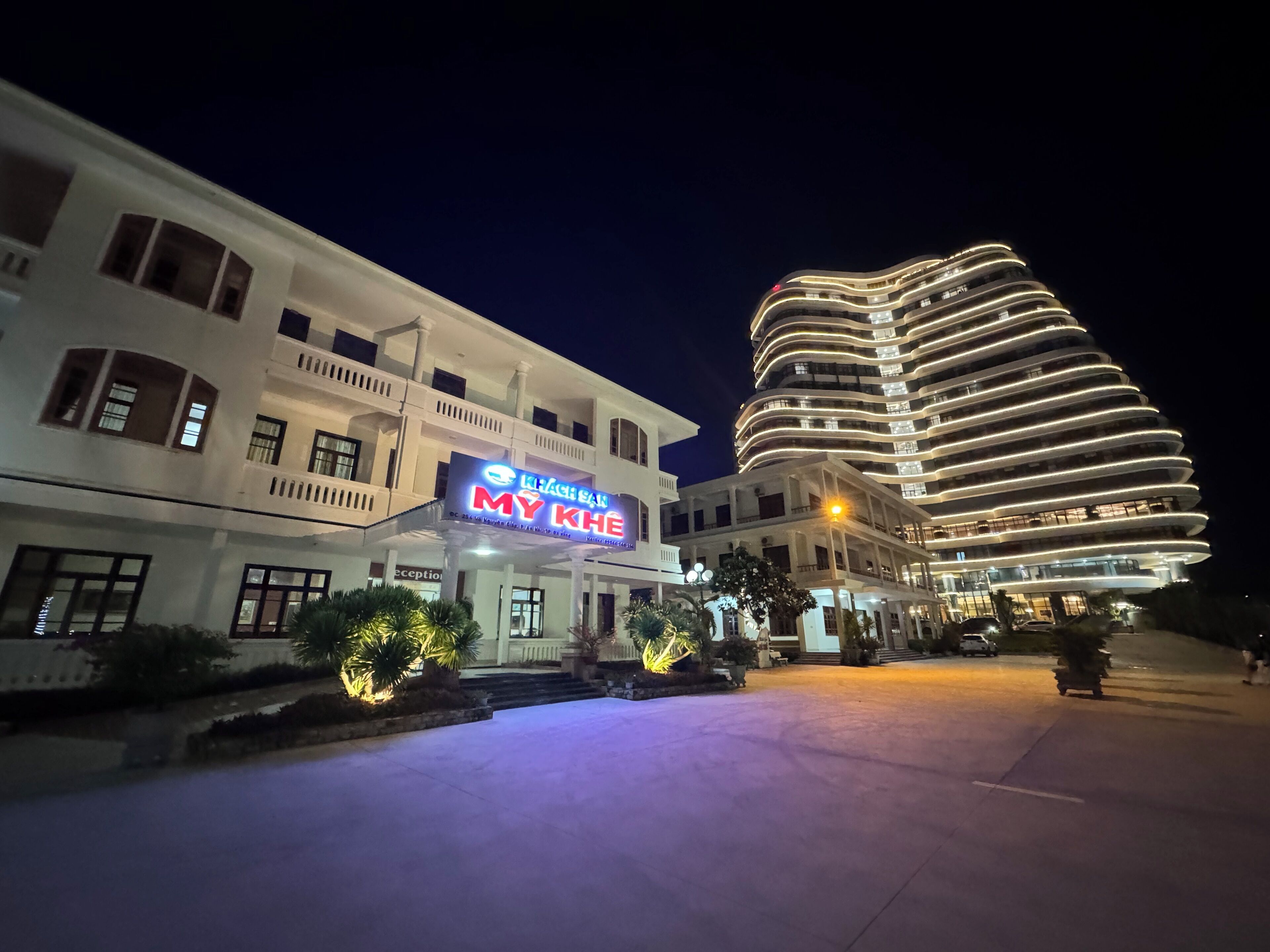 A hotel with a modern design, featuring a curved building and a signboard with the hotel's name.