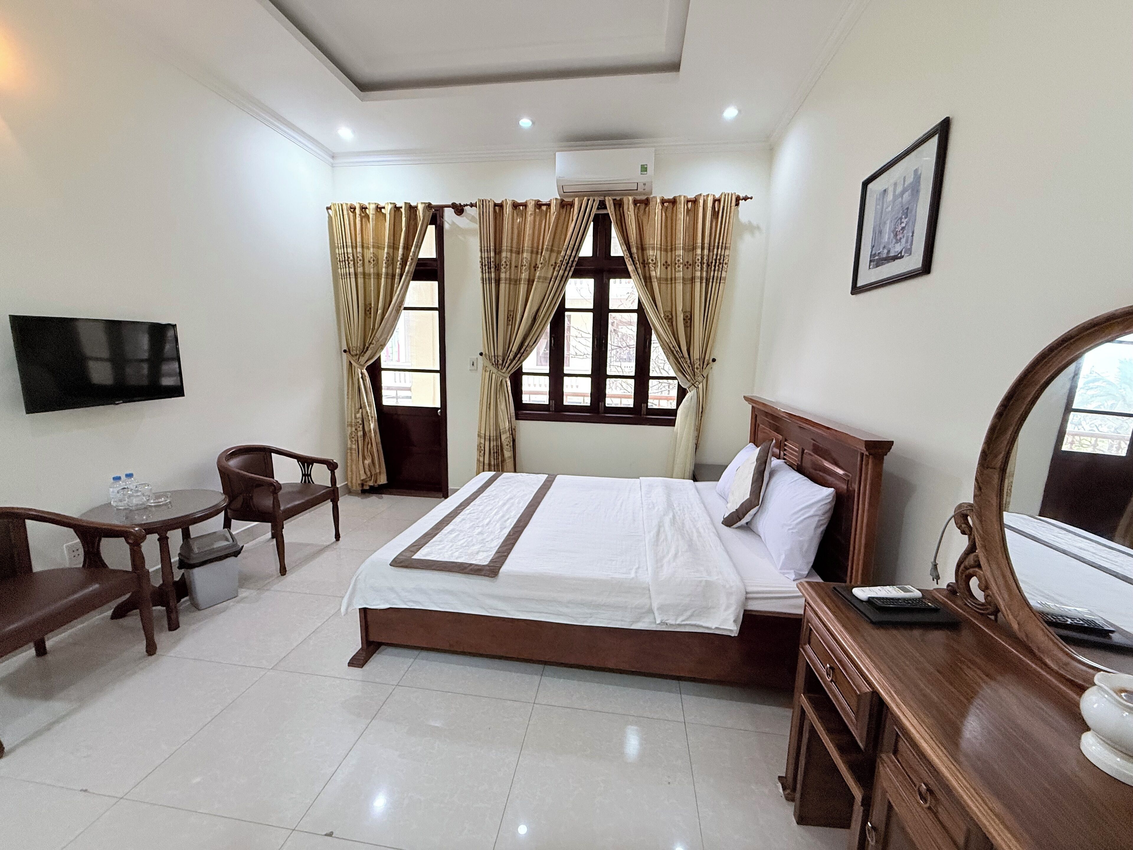 A hotel room with a bed, a desk, a chair, a TV, and a mirror.