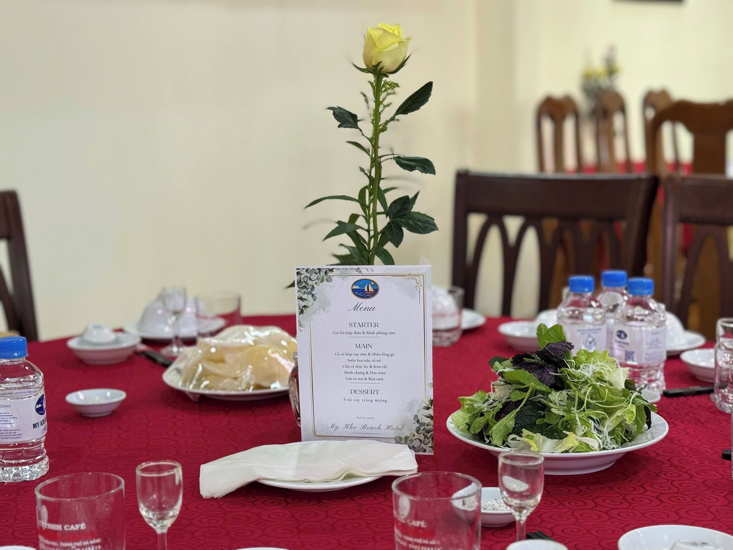 A dining table set with a menu, water bottles, and a salad.