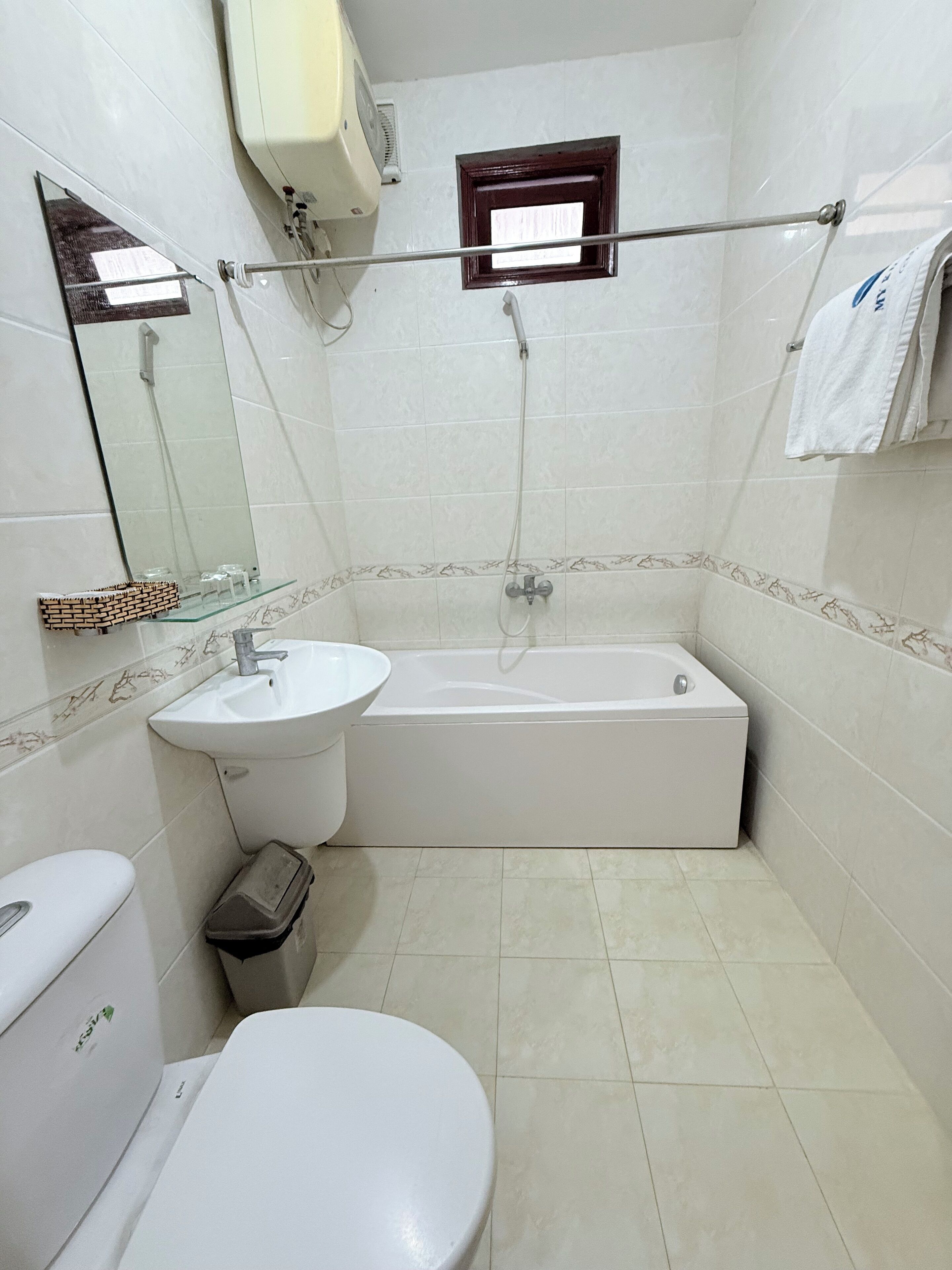 A bathroom with a toilet, sink, bathtub, and a small window.