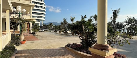 A hotel with a curved facade, outdoor seating, and palm trees.