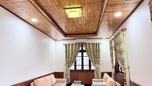 A spacious room with wooden panel ceilings, two sofas, a coffee table, and a window with curtains. - My Khe Beach Hotel (Da Nang)