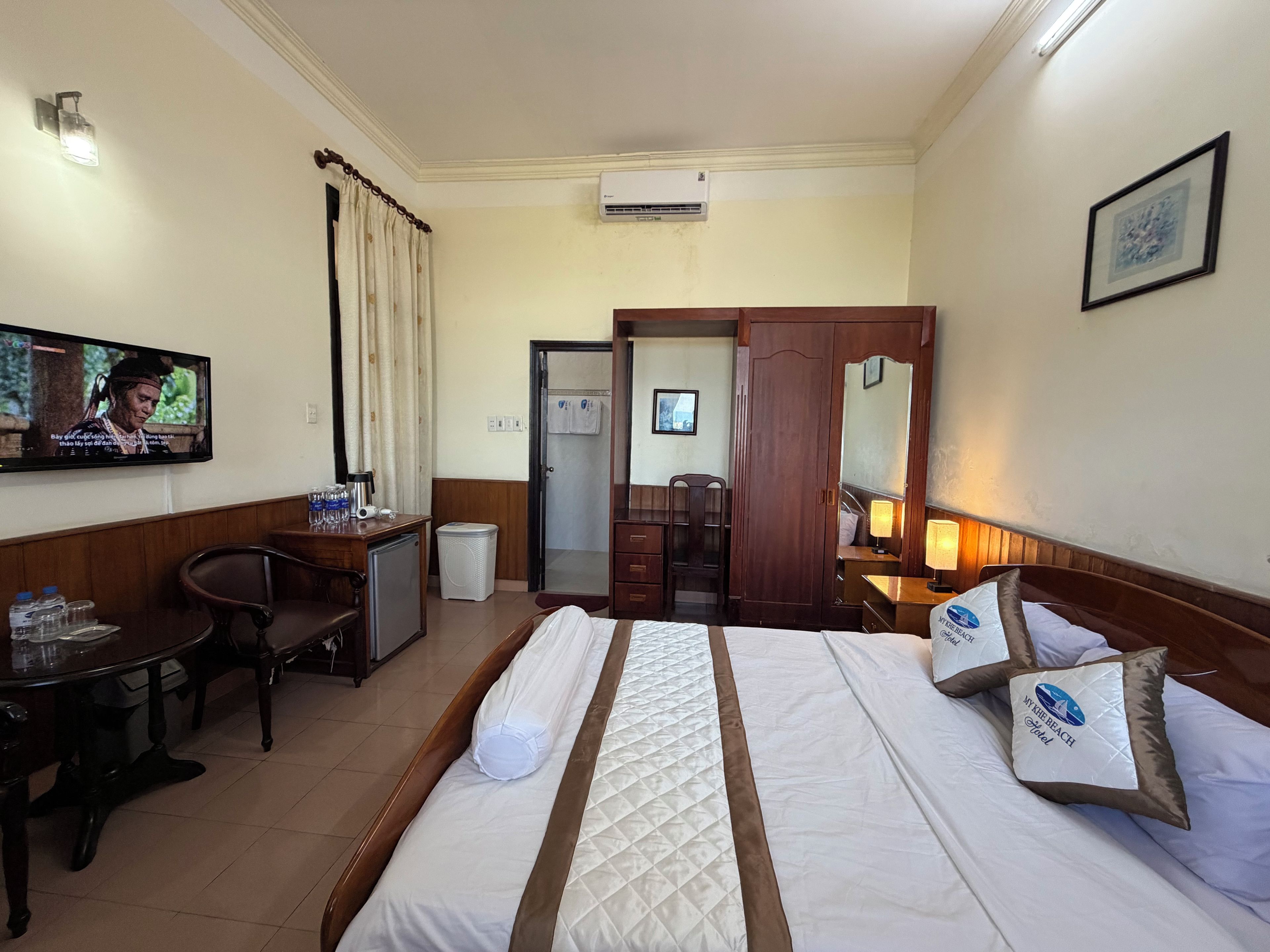 Una habitación de hotel con cama, escritorio, televisor, armario y baño.