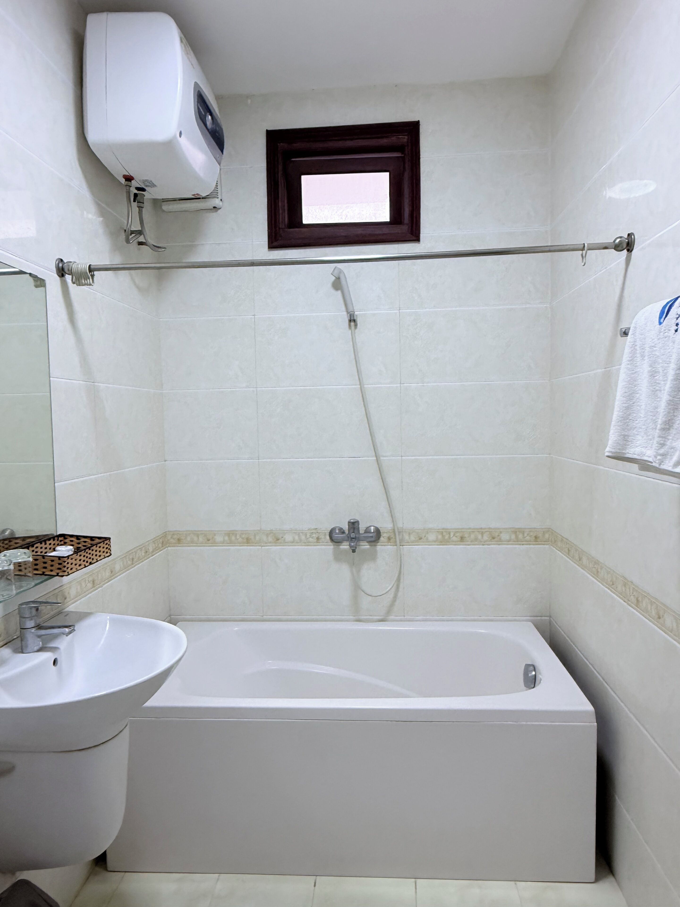 A bathroom with a bathtub, a sink, a towel rack, and a window.