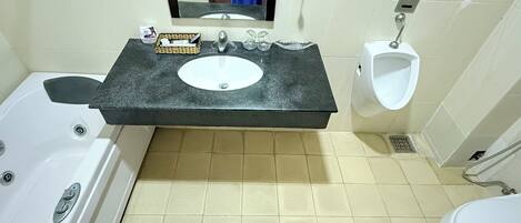A bathroom with a bathtub, a sink with a mirror, a urinal, and a toilet.