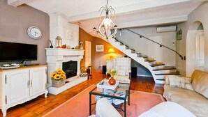 A living room with a fireplace, a television, and a staircase leading to another level. - Charming family home with heated pool in the Gard (Méjannes Lès Alès)