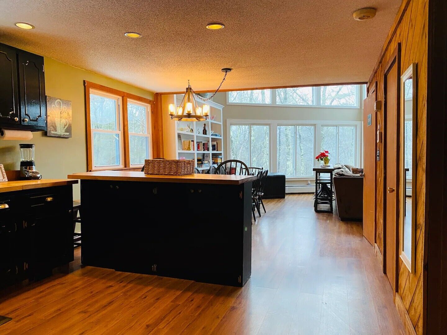 A spacious kitchen with a central island, wooden cabinetry, and a large window providing natural light.