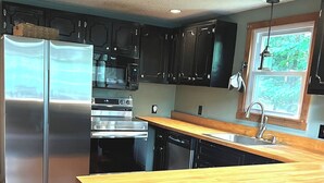 A modern kitchen with stainless steel appliances, wooden countertops, and a window with a view of greenery. - Mountain View, Dogs OK, 2 Kitchens, Screened Deck, Pool Table, North Conway (Conway)