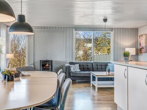 Una sala moderna con chimenea, un comedor y una cocina con armarios blancos.