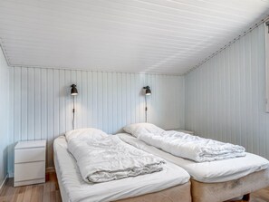 Una habitación con dos camas, una mesita de noche y dos lámparas de pared.