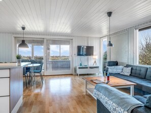 Una sala de estar moderna con suelo de madera, un sofá, una mesa de centro, un televisor y un balcón con vistas.