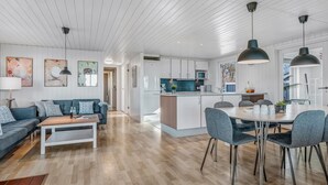 Une cuisine moderne avec des meubles blancs, un îlot central et des luminaires suspendus.