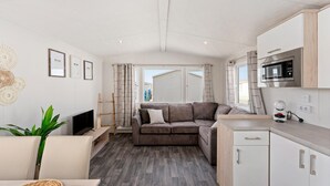 A modern, compact living space with a sofa, TV, and kitchenette. - Comfortable Mobile Home in Middelkerke (Middelkerke)