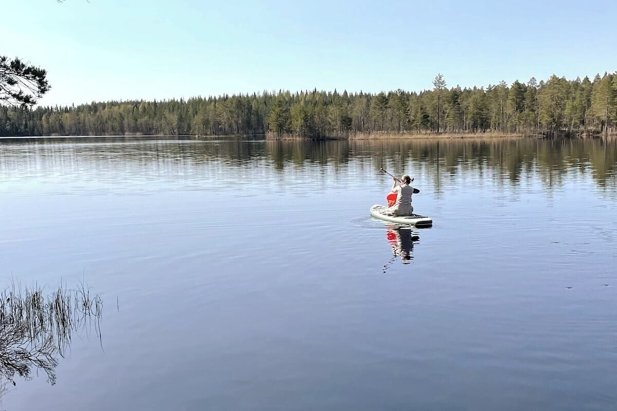 Un lago tranquillo con una persona su un'asse da paddleboard.