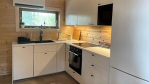 Una cocina compacta con armarios blancos, horno integrado y ventana sobre el lavamanos.