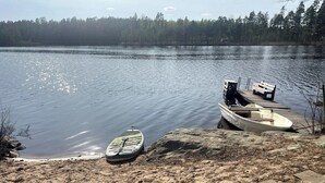 Una playa arenosa con un kayak y un bote pequeño amarrados a un muelle de madera.