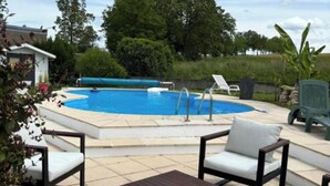 A swimming pool with a sunken seating area, surrounded by lounge chairs and a small table. - Country house with a change of scenery (Velet)