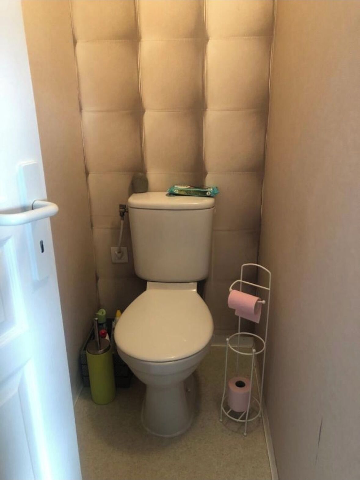 A small, compact bathroom with a beige toilet, a white sink, and a toilet paper holder.
