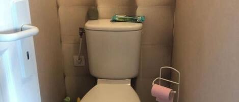 A small, compact bathroom with a beige toilet, a white sink, and a toilet paper holder.