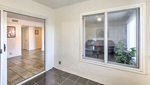 Ein Korridor mit einem großen Fenster, einer Tür zu einem weiteren Raum und einem Fliesenboden.