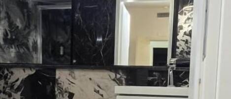 A bathroom with a bidet, a toilet, a mirror, and a vanity with a sink.