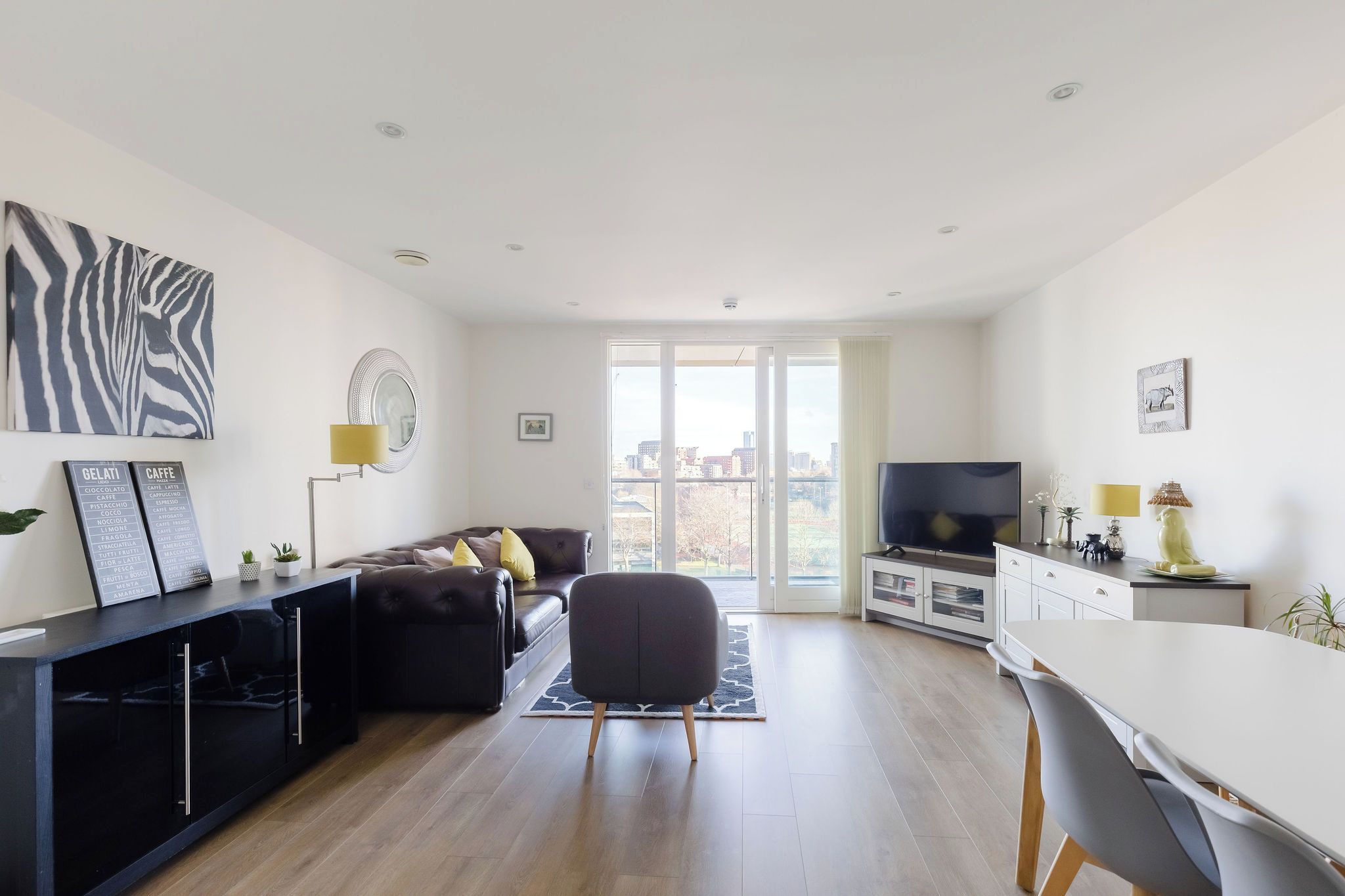 Een moderne woonkamer met een bank, een eethoek met een tafel, en een keukenruimte met een televisie.