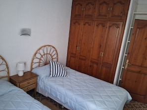 A bedroom with two beds, wooden wardrobe, and a bedside table with a lamp. - Fishermen's house in the port of Fornells (Aiguablava). (Fornells)