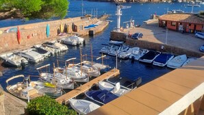 Una marina con barcos amarrados, un faro y un edificio en una colina.