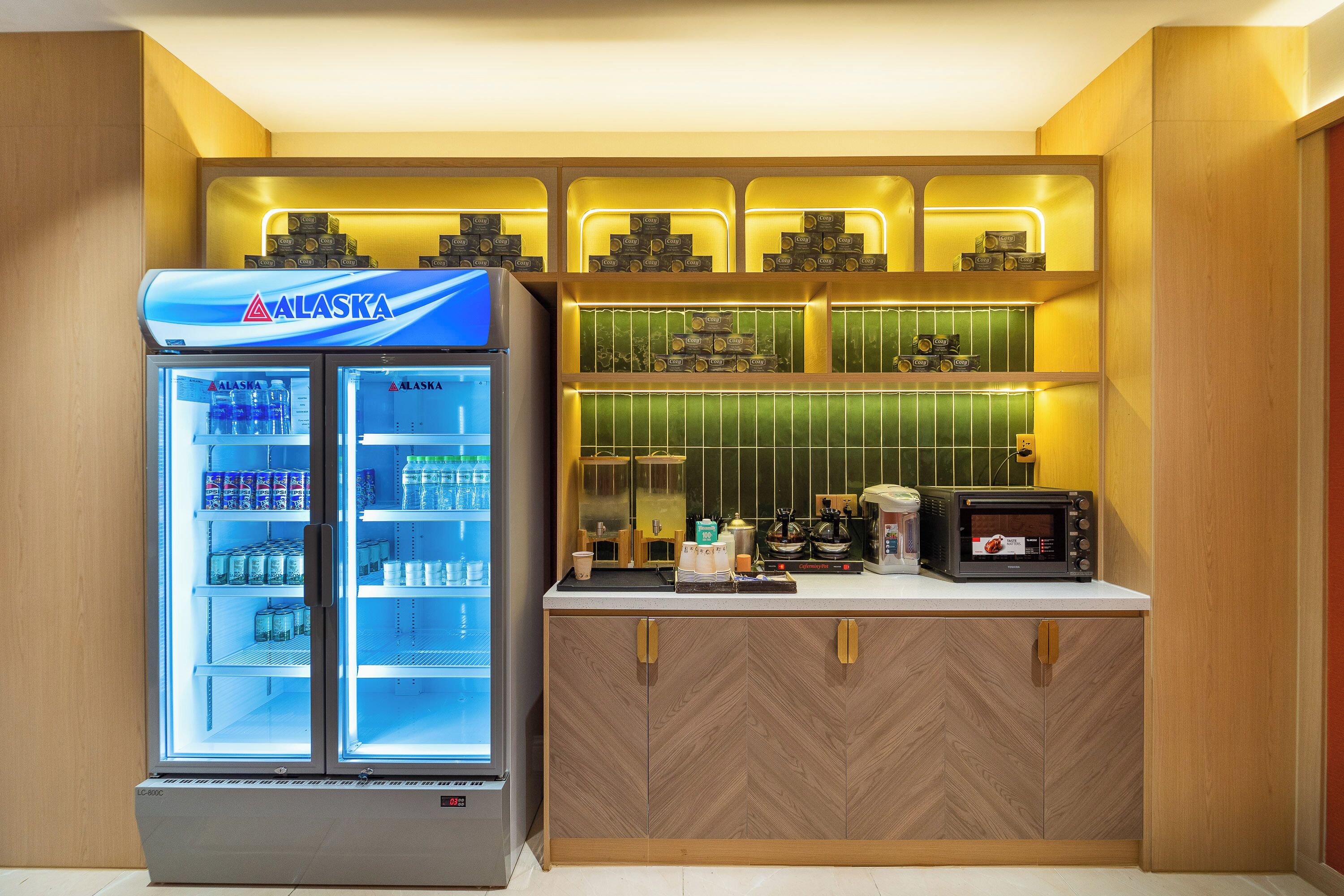A kitchenette with a refrigerator, microwave, and coffee machine.