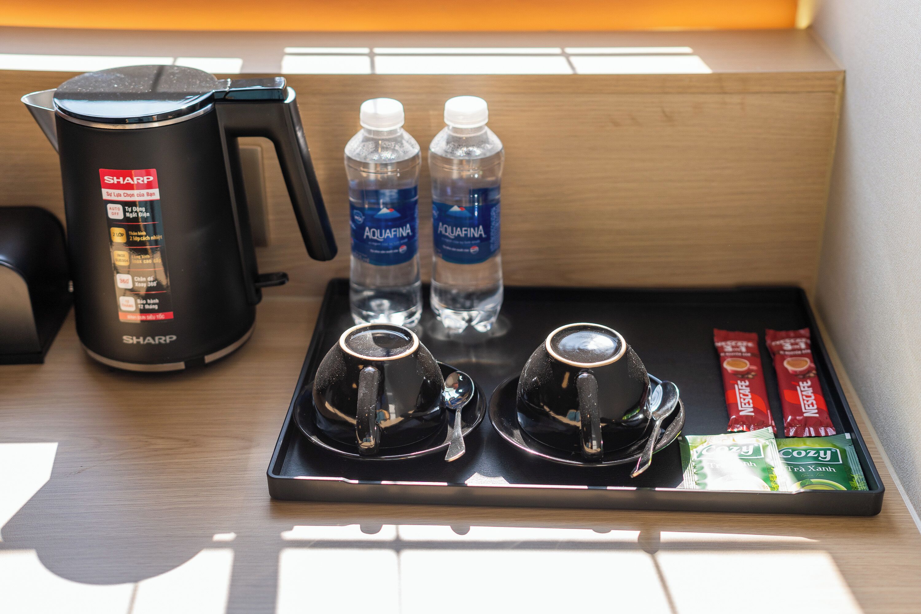 Eine Kaffeestation mit Kaffeemaschine, zwei Wasserflaschen, zwei Tassen und Kaffeekapseln.