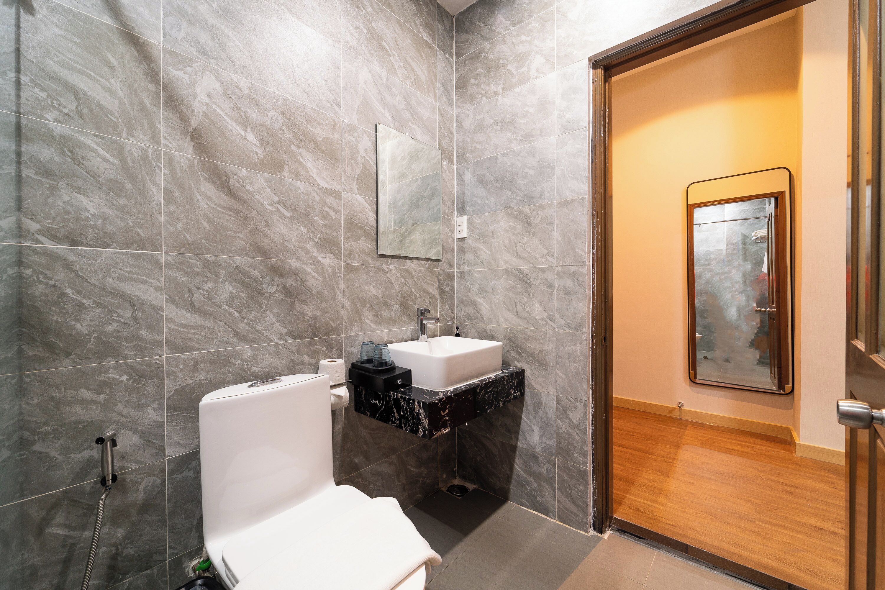 A bathroom with a toilet, sink, and mirror.