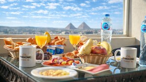 Ein Frühstückstisch mit Gebäck, Früchten, Saft und Wasserflaschen mit Blick auf eine schöne Berglandschaft.