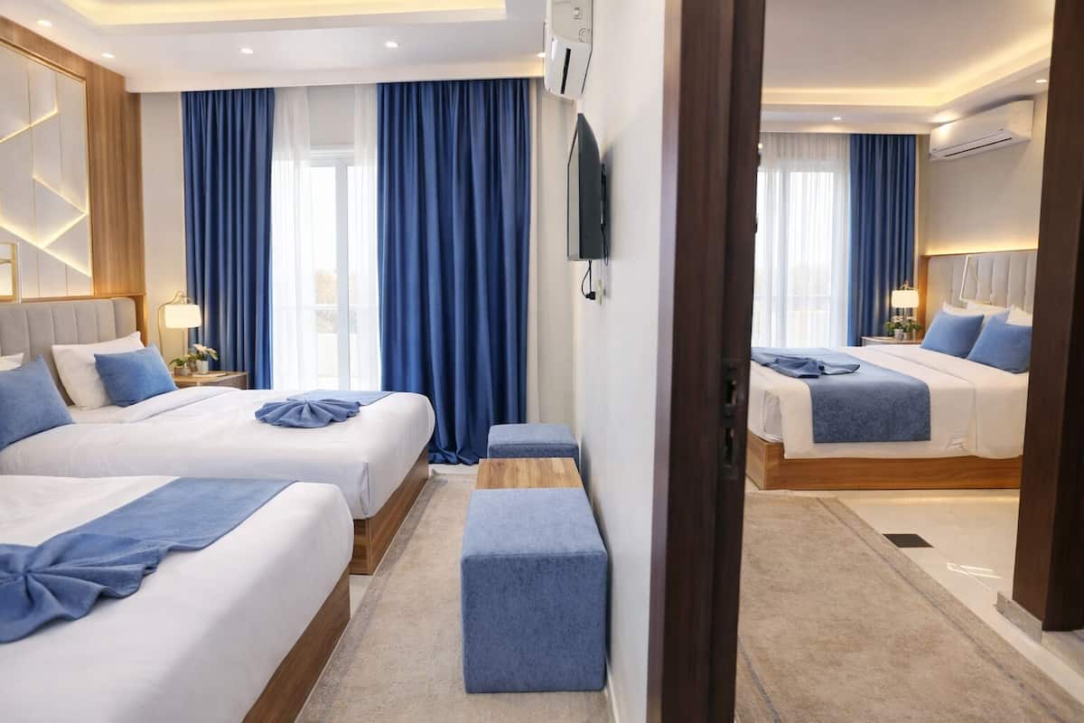 A hotel room with two beds, a TV, and a wooden headboard.