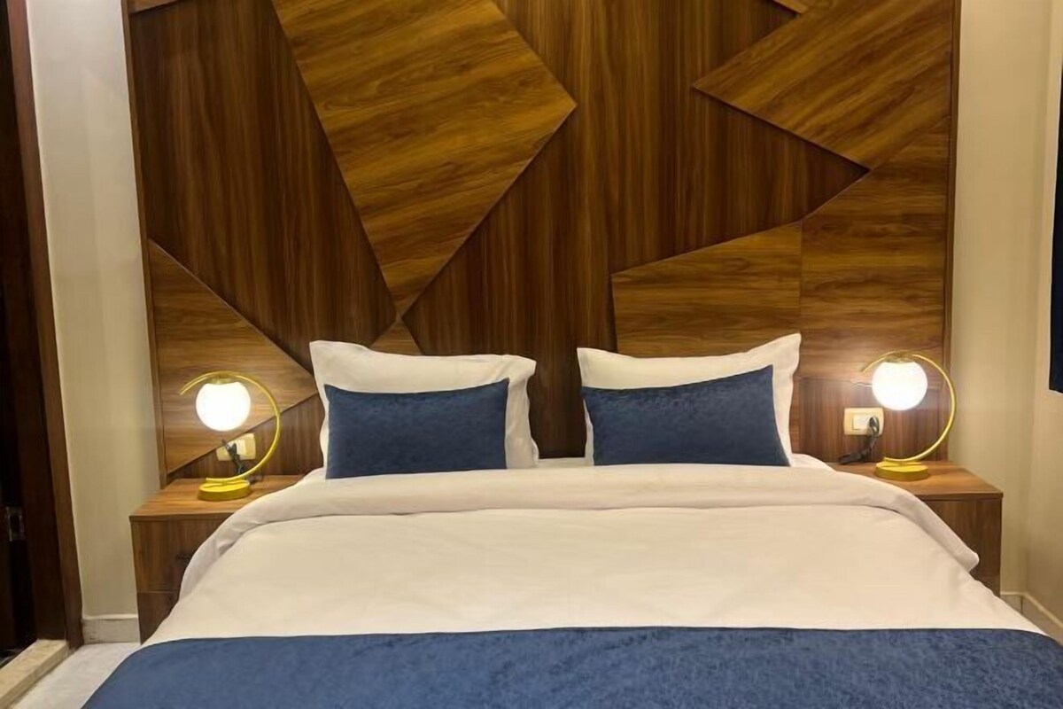 A bed with a white and blue bedspread, two blue pillows, and two bedside lamps with round lights.