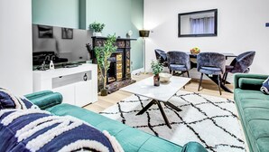A modern living room with a television, sofa, dining table, and chairs. - Large Semi-detached 4BD 3Bath Long Stay Discount, Wifi, Driveway Parking, Garage (Hounslow)