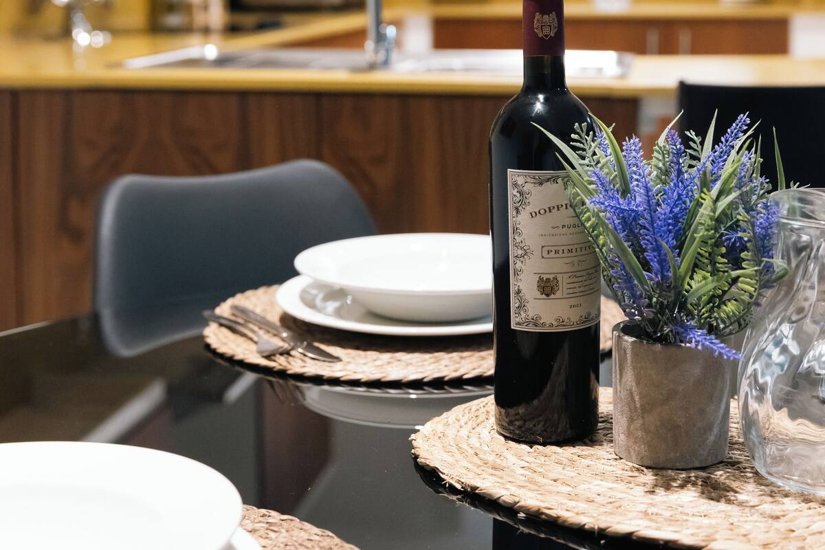 A dining table with plates, cutlery, a wine bottle, and a decorative plant.