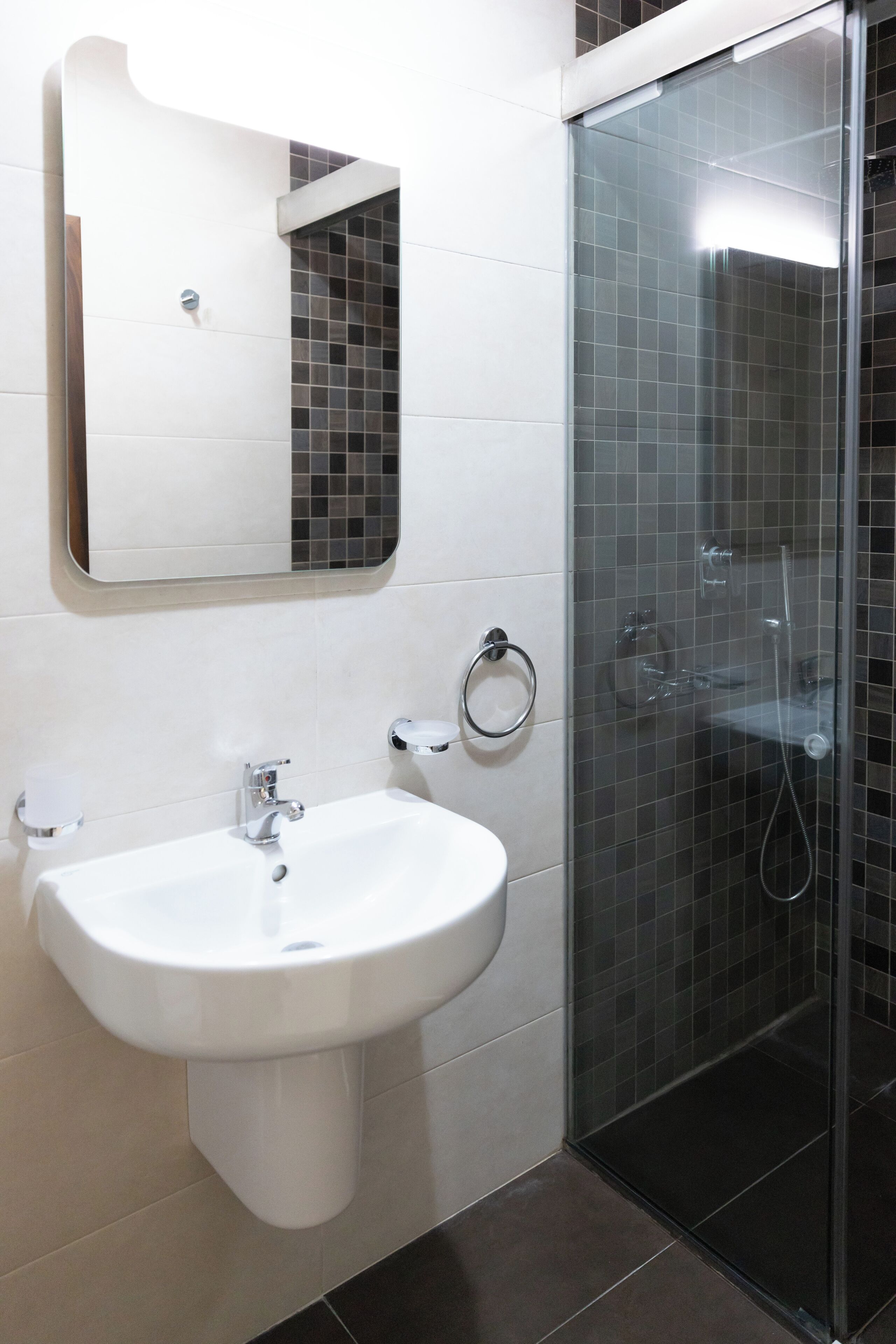 A bathroom with a white sink, a mirror, and a glass-enclosed shower.