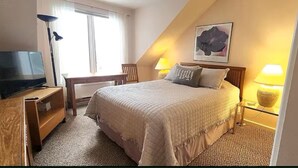 Une chambre à coucher avec un lit, un bureau, une chaise, une télévision et une lampe.
