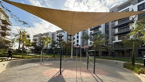 A circular outdoor area with exercise equipment, surrounded by a paved walkway and a large canopy. - Designer 2BR Serviced Apart at Cairo Festival City (Cairo Governorate)