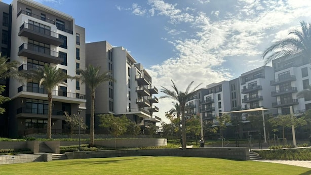 A modern apartment complex with multiple balconies, a well-maintained lawn, and palm trees. - Designer 2BR Serviced Apart at Cairo Festival City (Cairo Governorate)