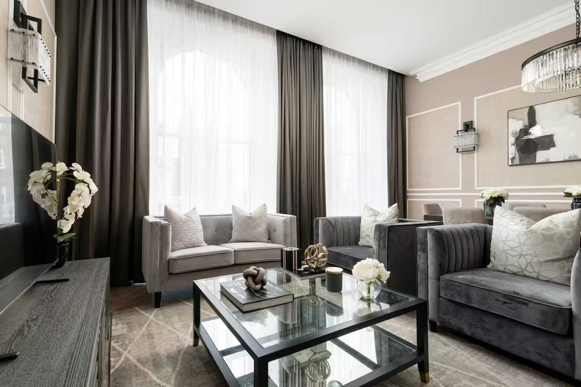 A modern living room with two sofas, a glass coffee table, and a vase of white flowers.