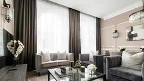 Un salon moderne avec deux canapés, une table basse en verre et un vase rempli de fleurs blanches.