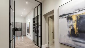 Un intérieur moderne comprenant une cuisine, un couloir avec des portes vitrées et un grand tableau abstrait.