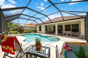 Ein überdachter Poolbereich im Freien mit Liegestühlen, einem Tisch mit Pflanze und einer Terrasse mit Essgruppe.