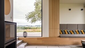 A modern living room with a large window, a built-in seating area, and a minimalist design. - Fantastic vacation rental with wide views of valley, forest and own vineyard! (Zonnebeke)