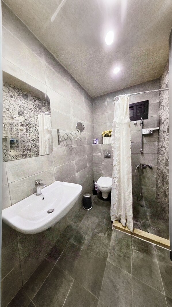 A bathroom with a large sink, toilet, and shower area.