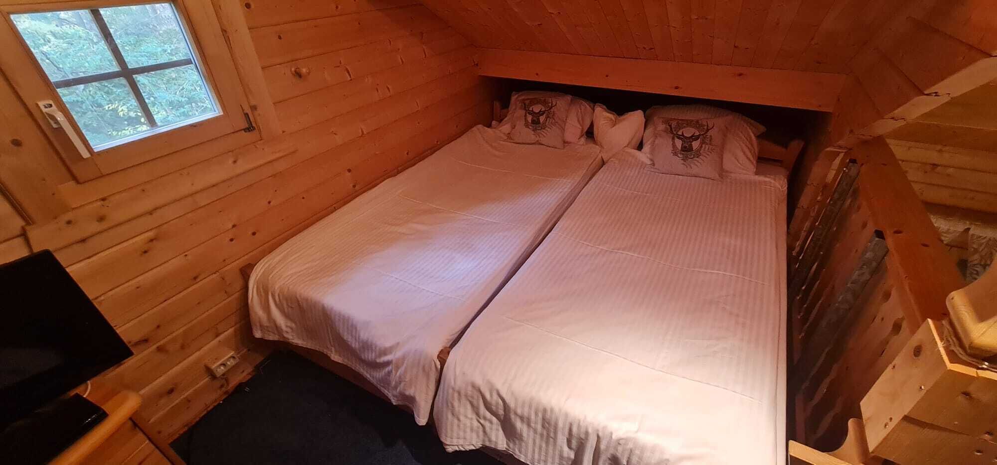 En liten, mysig stuga med en enkelsäng, en prydnadskudde och ett fönster med utsikt över träd.