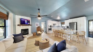 A modern living room with a sofa, coffee table, and a TV mounted on the wall. - Relax and Play - Heated Pool + Game Shed + Minutes to the Beach (St. Augustine)